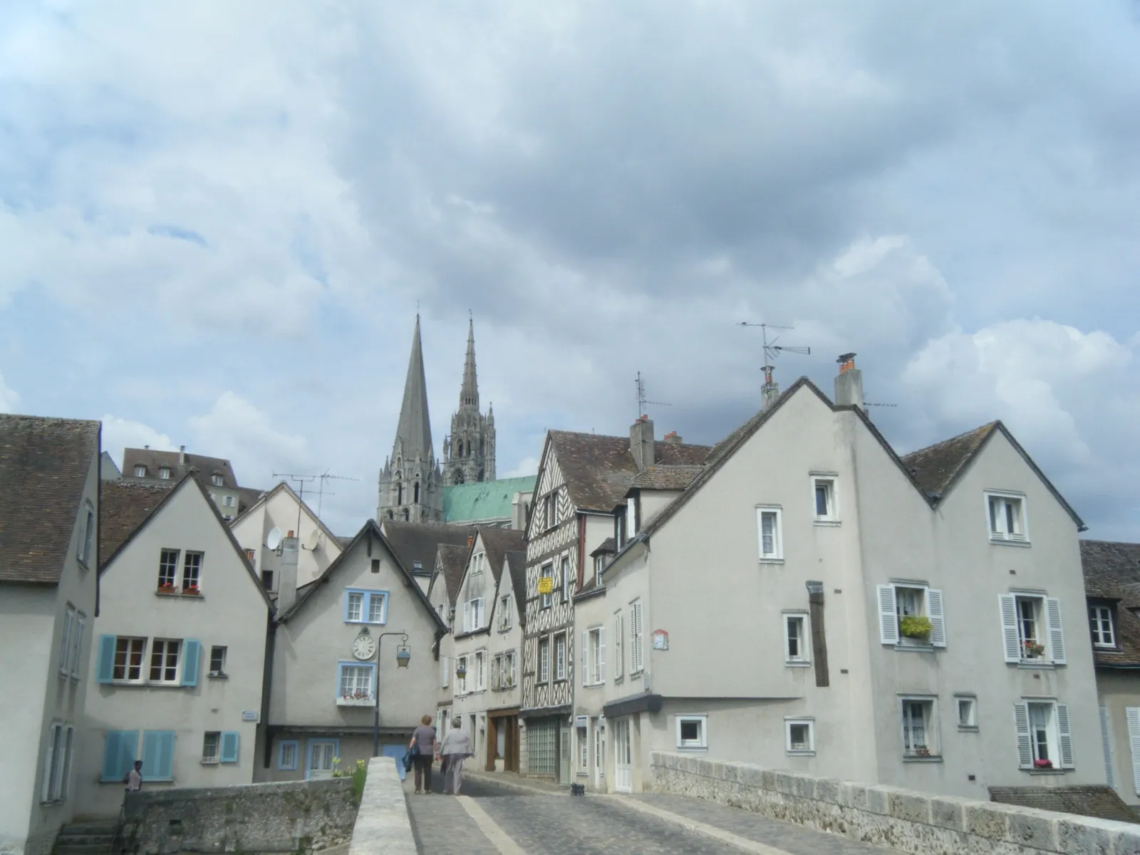 Rue pavée de la basse ville de Chartres bordée de maisons anciennes, avec les deux flèches de la cathédrale en arrière-plan